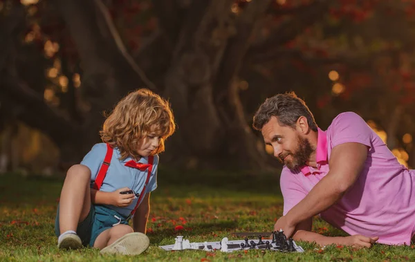 Hraje šachy s otcem. Dítě hraje deskovou hru s rodičem. — Stock fotografie