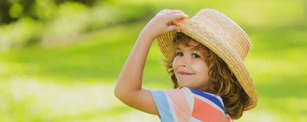 Banner con cara de niño primaveral. Retrato de niño alegre en el parque natural de verano. Lindo niño alegre. Primer retrato de un niño divertido con sombrero de paja. Vacaciones de verano. — Foto de Stock