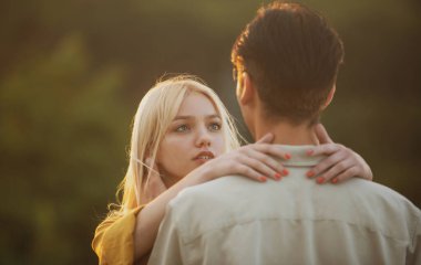 Gün batımında sarılıp öpüşen aşıklar. Genç aşık bir çift birlikte zaman geçirir. Erkeğin kucaklaması ve şehvetli bir kadını öpmesi.