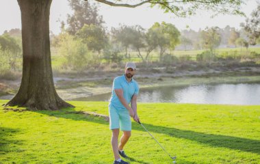 Golfçü yeşil golf topuna vuruyor..