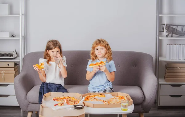 Funny kids eating pizza. Two young children bite pizza indoors. — Stock Photo, Image