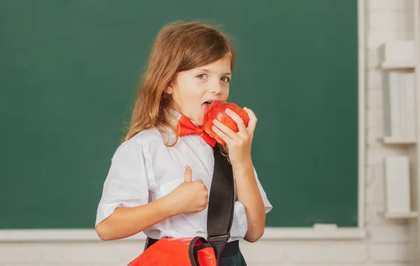 Retrato de la encantadora niña con manzana roja en el aula. Niño genio, día del conocimiento. —  Fotos de Stock