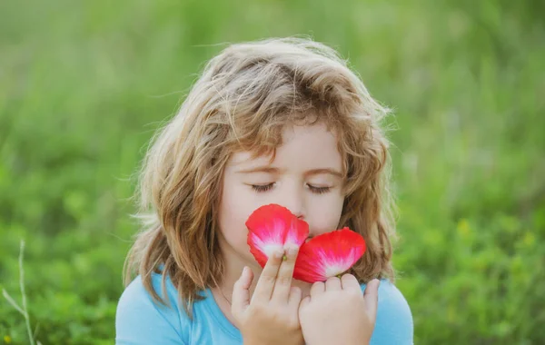 Gros plan sur la tête d'un enfant qui sent les fleurs dans un parc naturel printanier. Visage d'enfant, portrait de petit garçon. Humeur printanière, bénéficie d'une odeur agréable. — Photo