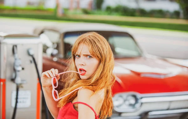Σέξι γυναίκα στο βενζινάδικο. Κομψή κυρία κατά του κόκκινου ρετρό αυτοκινήτου. — Φωτογραφία Αρχείου