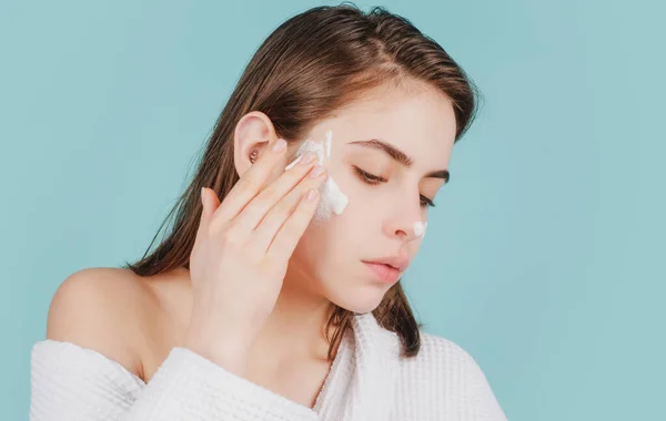 Beautiful young woman with clean fresh skin. Cute young girl preparing to start her day, applying moisturizer cream on face. — Stock Photo, Image