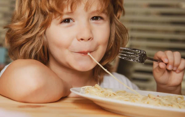 Criança branca sorrindo comendo macarrão, espaguete, retrato de perto. Cara de crianças. — Fotografia de Stock