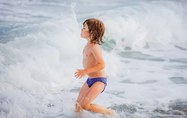 Kid boy spelen en plezier hebben op het strand op de blauwe zee in de zomer. Blauwe oceaan met waden. Kind jongen zwemmen in zee. — Stockfoto