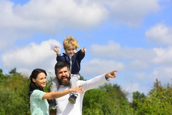 Kind spielt mit Spielzeugflugzeug und träumt Zukunft, Konzept von Träumen und Reisen. Glückliches Familienporträt, das Spaß zusammen mit Spielzeugpapierflugzeug hat. Vater Mutter und Kind Sohn. — Stockfoto