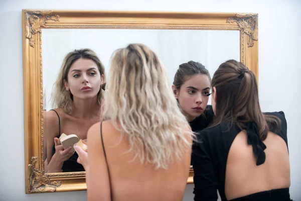 Μακιγιάζ, εφαρμογή καλλυντικών. Γυναίκες φιλενάδες που ετοιμάζονται για πάρτι, κοιτάζονται στον καθρέφτη. Όμορφο γυναικείο πρόσωπο. Συμπληρώνεται κατά τη διαδικασία. — Φωτογραφία Αρχείου