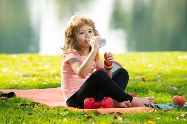 Çocuk sağlıklı besleniyor, egzersizden sonra su içiyor..