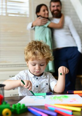 Evde çizim yapan anne ve babası olan bir çocuk. Aile tatili ve birliktelik. Anne, baba ve çocuk, tatil ve birliktelik. Erken dönem sanat ve zanaat eğitimi, çizim.