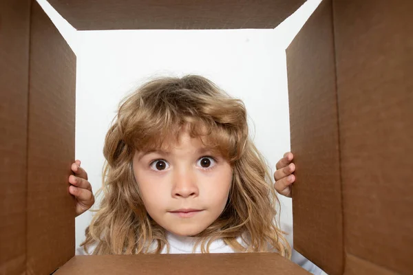 Joyeux petit garçon ouvre cadeau et regarder à l'intérieur de la boîte en carton. Parcelles et livraison. — Photo
