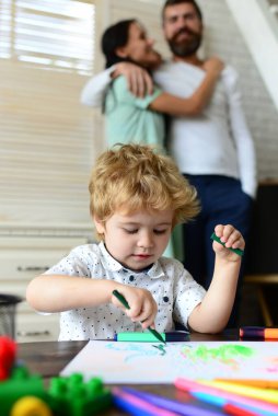 Mutlu aile eğleniyor, ebeveynler ve küçük çocuk birlikte oynuyor. Neşeli oğul, anne ve babasıyla resim çiziyor ve eğleniyor. Çocuk resim öğrenme, küçük ressam resmi, çizim.