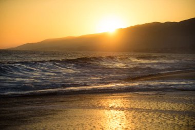 Deniz yüzeyinin altında büyük sarı güneşli bir gün batımı. Sakin okyanus, gün batımında gökyüzü ve bulutların arasında güneş. Sakin okyanus ve gökyüzü arka planı. Cennet plajı.