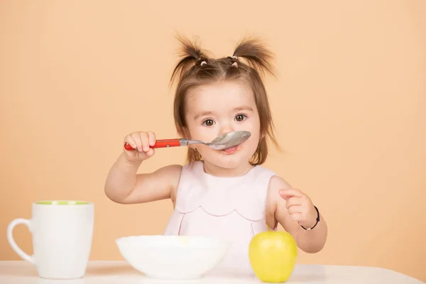 Baby 's eten, gezond voedsel voor een baby. Kind eet gezond voedsel met een lepel in de studio, geïsoleerd. Grappige kinderen gezicht. — Stockfoto