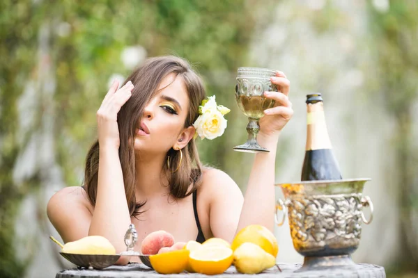 Sexy woman with fresh fruit on a table in park outdoors. Sensual young woman drink champagne. — Stock Photo, Image