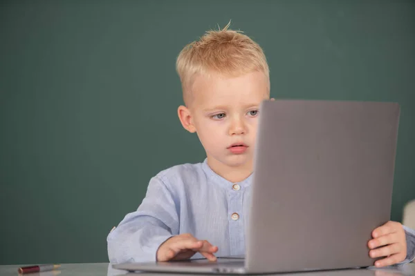 Basisschooljongen die in computerles werkt. Leuke pupil gezicht close-up op schoolbord achtergrond. — Stockfoto