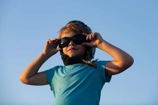 Ragazzino con occhiali da pilota e casco, il ragazzo vuole diventare pilota e astronauta. Bambino felice gioca in cielo. Bambini pilota sogna di volare. — Foto Stock
