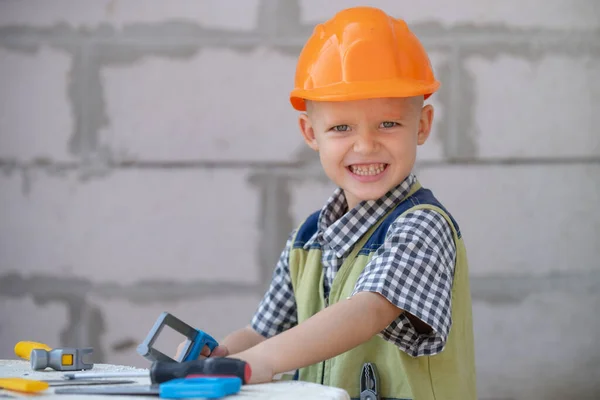 Kind in een helm, harde hoed. Reparatie thuis. Kind verkleed als arbeider bouwer. Portret kleine bouwer in hoeden. Kleine bouwer in helm. — Stockfoto