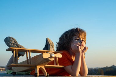 6 yaşındaki bir çocuk parkta oyuncak bir uçakla oynuyor. Seyahat hayalleri. Geliştirme, büyüme, hayaller ve planlar. Hayal gücü ve rüya konsepti.