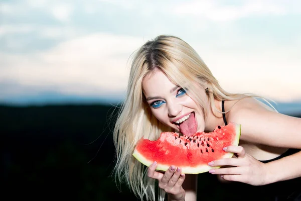 Sexy zomer tropisch fruit. Sensuele jonge vrouw likt watermeloen met sexy tong. Grappig mooie jonge blonde vrouw met blauwe ogen die watermeloen eet. Sexy mond bijten watermeloenen. — Stockfoto