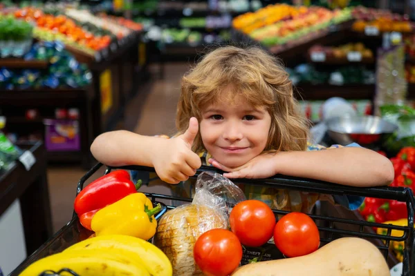 Çocuklar süpermarketten alışveriş yapıyor. Küçük çocuk marketten taze sebze seçiyor..