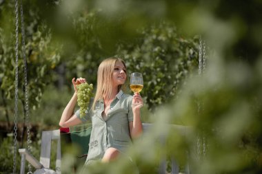 Beyaz üzümden yapılmış el yapımı şarap. Yüzüne bir demet üzüm tutan çok seksi bir genç kadın..