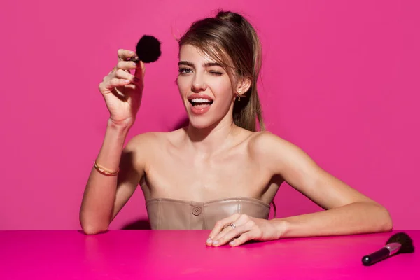 Maquillaje sexy para la fiesta. Hermosa mujer joven sensual con pincel colorete maquillaje, maquillaje sexy, retrato de cerca sobre fondo rosa aislado. —  Fotos de Stock