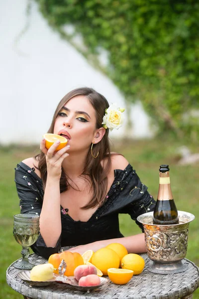 Schöne sexy Frau im Garten, die tropische Früchte isst, Sommerurlaub. Schöne Frau isst Orange und genießt den Frühling, hübsches Mädchen entspannt im Freien. — Stockfoto