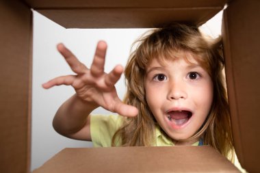 Çocuk karton kutunun içine bakıyor, alt manzara. Satın aldıklarınızı teslim ediyorum. Çocuklar doğum gününü kutlar. Doğum günü hediyesi. Çocuk açma paketi.