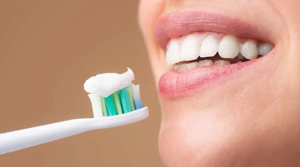 Cepillo de dientes con pasta de dientes. Joven mujer alegre cepillarse los dientes con cepillo de dientes durante los procedimientos de higiene matutina aislado de fondo,. Boca de cerca con cepillo de dientes. —  Fotos de Stock