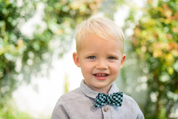 Gelukkig kind met vlinderdas, schattig lief kind. Joyful portret van klein kind op groene natuur achtergrond buiten. — Stockfoto