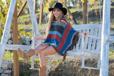 Yazın salıncakta sallanan boho tarzındaki şehvetli hippi kadın, bahar parkında şapka takan genç seksi kız. Özgürlüğün tadını çıkaran ve tasasız hisseden genç bir kadın..