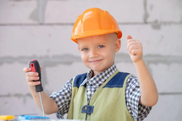 Little boy in orange protective helmet with instruments for renovation. Smiling happy kids builder and repair. — Stock Photo, Image