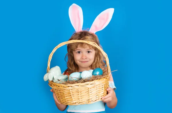 Кролик хлопчик з пасхальним кошиком ізольований на синьому фоні. Діти хлопчик у кролячих вухах полюють на великодні яйця. Полювання на великодні яйця. Смішні діти стикаються . — стокове фото