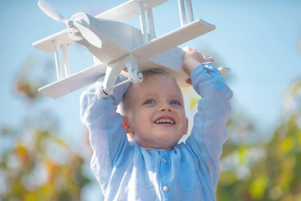 Divertido niño o niño pequeño piloto jugar con el avión de juguete, la libertad de inicio y despreocupado. Sueños de vuelo. Niño jugando con un avión de juguete contra el cielo. Niño rubio, cara de emoción sonriente. — Foto de Stock