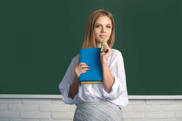 Πορτρέτο των νέων χαριτωμένο ξανθιά φοιτήτρια θηλυκό κολέγιο που σπουδάζουν στην τάξη στην τάξη με φόντο πίνακα. — Φωτογραφία Αρχείου