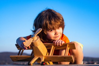 Komik çocuk ya da çocuk pilot oyuncak uçakla oynuyor, başlangıç özgürlüğü ve tasasız. Uçma hayalleri. Çocuk gökyüzüne karşı oyuncak uçakla oynuyor. Tatlı çocuk suratı..