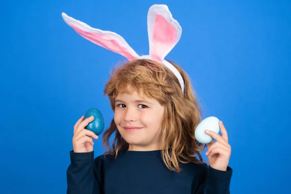 Portrait d'enfant avec des œufs de Pâques colorés isolés sur fond bleu. Des enfants chassant des œufs de Pâques. Visage drôle d'enfants. — Photo