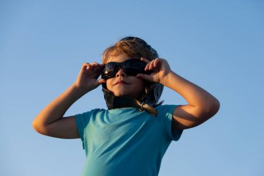 Komik çocuk ya da çocuk pilot pilot pilot pilot pilot gözlük ve miğferle oynuyor, başlangıç özgürlüğü ve tasasız. Uçma hayalleri. Gökyüzüne karşı oynayan çocuk.