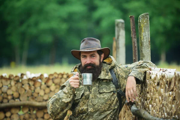 Retrato de hombre viajero con mochila senderismo al aire libre. Viajar estilo de vida rural y concepto de aventura. Hombre tomando té o café caliente con taza de esmalte, taza al aire libre. —  Fotos de Stock