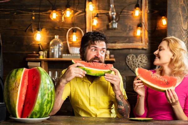 Couple mangeant pastèque dans la cuisine. Un homme et une femme mangent de la pastèque à la maison. Un couple heureux qui mange de la pastèque. Couper mari tranches de pastèque pour femme. — Photo