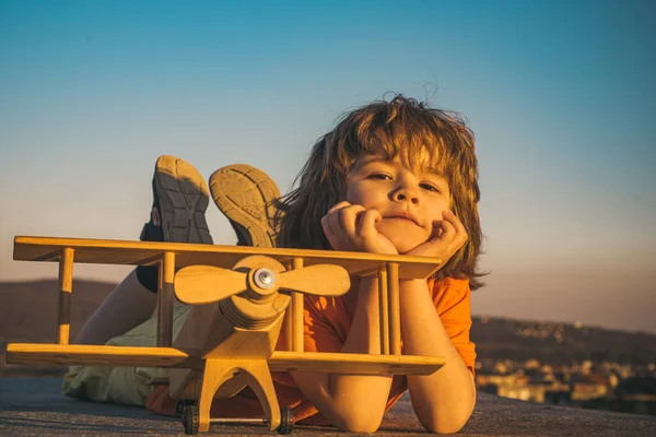 Child pilot with toy airplane dreams of traveling in summer in nature. Kids dreams. Child plays with a toy plane and dreams of becoming a pilot. Summer holidays with children. — Stock Photo, Image