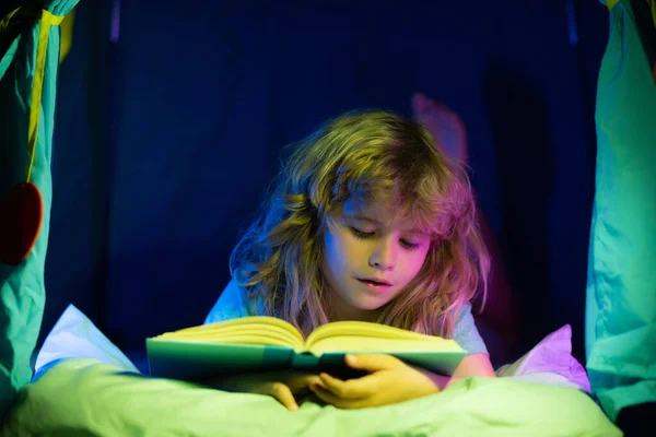 Libro de lectura infantil. Niños, hora de dormir. Niño leyendo un libro en la cama. —  Fotos de Stock