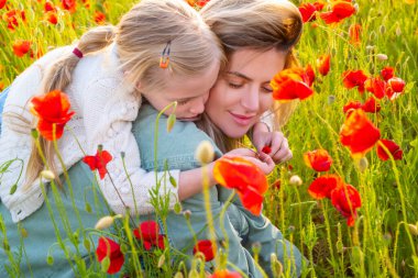 Anne ve kızı gelincik çayırında sarılıyorlar. Anne ve kız gelincik çiçekleriyle tarlada dinleniyorlar. Anne ve kızı baharda.