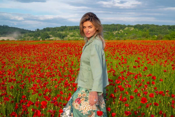 Happy woman resting on a beautiful poppy field. Girl having fun spring outdoor. Woman in field with red poppies. — Stock Photo, Image