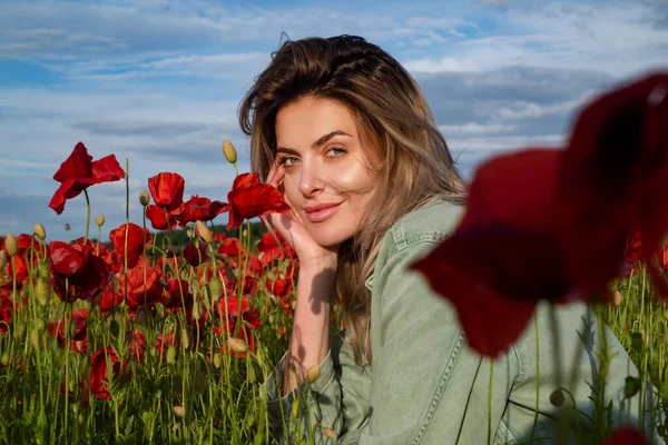 Portrait of a beautiful woman in a field of red poppies enjoys nature. A young woman in a poppy field. Spring girl. — Stock Photo, Image