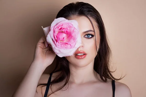 一个带着玫瑰花的女人的画像。美容美发模特脸。脸庞上有一朵粉色玫瑰的年轻漂亮姑娘的画像. — 图库照片