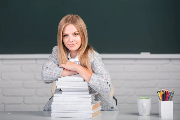 Estudiante de clase en clase en la escuela secundaria o la universidad. Linda chica estudiante con libros en el fondo de pizarra con espacio de copia. — Foto de Stock