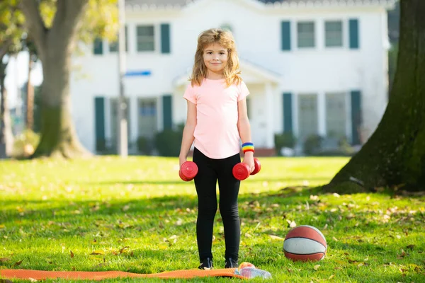 Niños deportistas. Niños haciendo ejercicio. Deporte actividades para niños al aire libre. Niño criando una mancuerna. —  Fotos de Stock